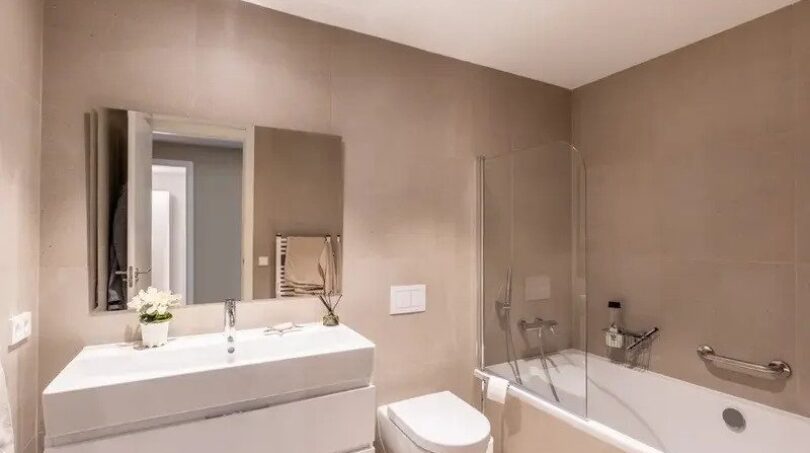 Modern bathroom of the new ground-floor apartment in La Vileta with bathtub, shower and white sink.