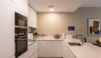 Modern white fitted kitchen with Bosch appliances, quartz stone worktops and kitchen island in new ground-floor apartment La Vileta