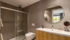 Modern bathroom of the new ground-floor apartment in La Vileta with glass shower, wall-hung WC and round mirror.