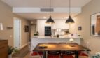 Open-plan kitchen with white fitted kitchen, dining table and black pendant lights in new ground-floor apartment La Vileta