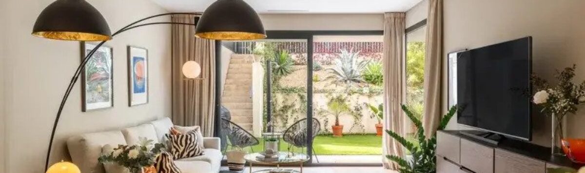 Bright living-dining area with wooden table, black pendant lights and access to the green garden