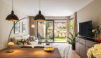 Bright living-dining area with wooden table, black pendant lights and access to the green garden