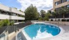Oval outdoor pool with glass railing and modern residential buildings in the new La Vileta complex, Palma