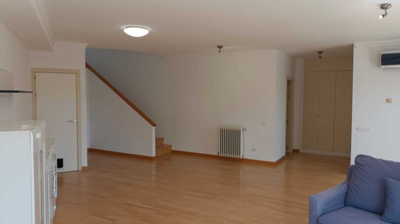 Bright living room with wooden floor, staircase, radiator and blue sofa in the La Vileta townhouse