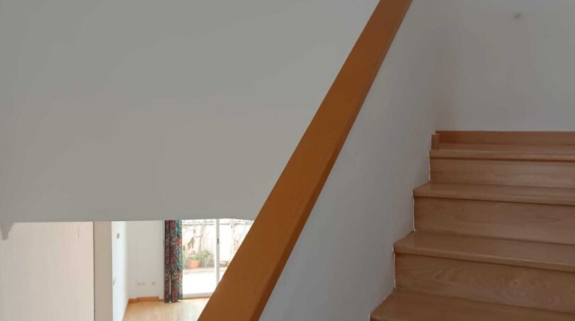 Bright stairwell with wooden steps and white railing in the exclusive townhouse in La Vileta, Palma