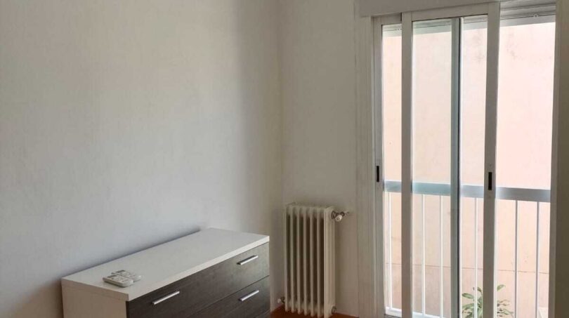 Bright bedroom with wooden floor, dresser, radiator and balcony door in the La Vileta townhouse