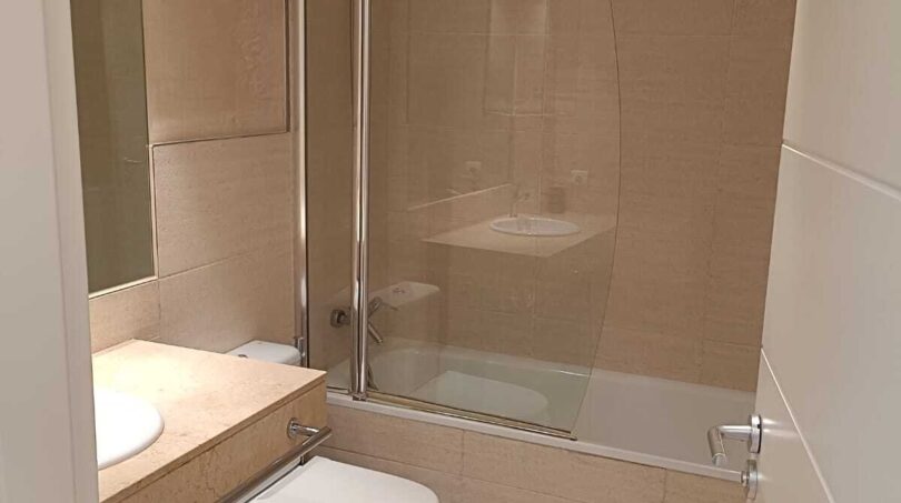 Bright bathroom with bathtub, shower, toilet and beige marble in La Vileta townhouse, Palma