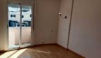 Helles leeres Schlafzimmer mit Holzboden, Wandleuchte und Glasschiebetür zum Balkon im Reihenhaus La Vileta