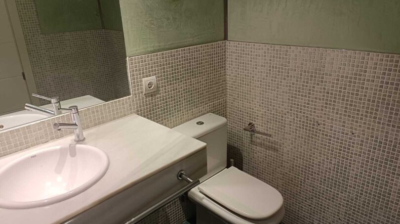 Bathroom with mosaic tiles, built-in sink and toilet in the La Vileta townhouse, Palma de Mallorca.