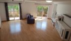 Helles Wohnzimmer mit Parkettboden, blauem Sofa und zwei Terrassentüren zum Garten im Reihenhaus La Vileta