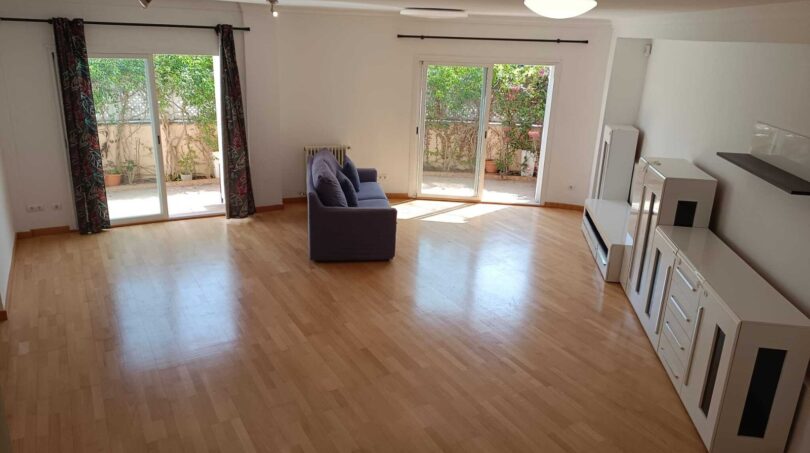 Bright living room with parquet floor, blue sofa and two terrace doors to the garden in the La Vileta townhouse