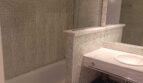 Badezimmer mit Mosaikfliesen, Einbaubadewanne, Glastrennwand und elegantem Waschtisch im Reihenhaus La Vileta