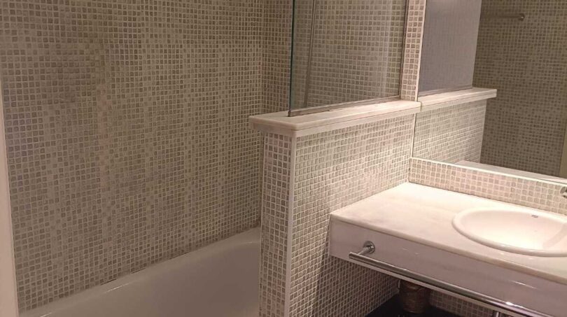 Bathroom with mosaic tiles, built-in bathtub, glass partition and elegant washbasin in the La Vileta townhouse