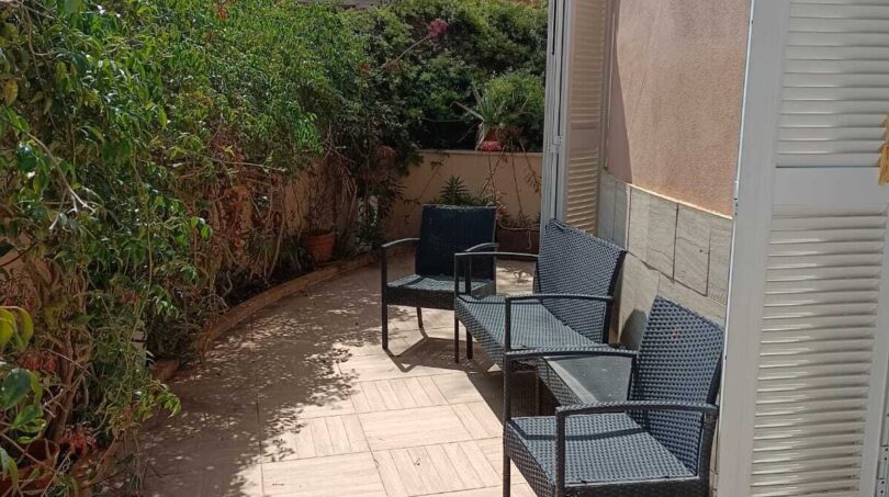 Sunny terrace with rattan furniture and lush greenery at the townhouse in La Vileta, Palma