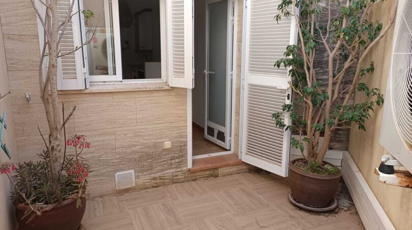 Sunny courtyard of the townhouse in La Vileta with terracotta tiles, potted plants and access to the kitchen.