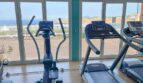 Fitnessraum mit Laufbändern und Ellipsentrainer, großen Panoramafenstern und Meerblick in El Toro