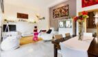 Helles Wohnzimmer mit Esstisch, bunten Kunstwerken, weißen Möbeln und orangem Teppich in Palma de Mallorca