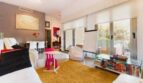 Helles Wohnzimmer mit goldfarbenem Teppich, Glasfront zur Terrasse und modernem Kinderspielbereich in Palma