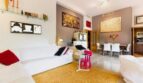 Helles Wohnzimmer mit weißen Sofas, goldenem Teppich und modernen Kunstwerken in Palma de Mallorca