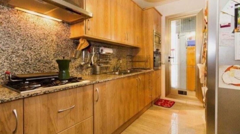 Moderne Küche mit Holzfronten, Granitarbeitsplatte, Gasherd und Einbaugeräten in Erdgeschosswohnung Palma