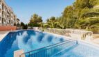 Gemeinschaftspool mit weißem Zaun, Palmen und mehrstöckigem Wohngebäude in Palma de Mallorca