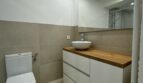 Modernes Badezimmer mit weißem Waschtischunterschrank, Holzabdeckung, Aufsatzwaschbecken und beigen Wandfliesen im Penthouse Palma