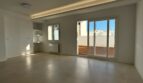 Helles, leeres Wohnzimmer mit Terrassenzugang, Betonboden und indirekter Beleuchtung im Penthouse Palma