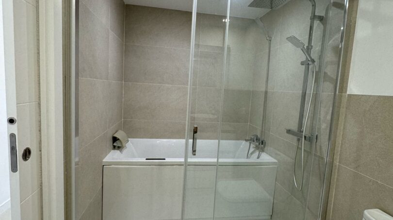 Modernes Badezimmer im Penthouse mit Glasdusche, Badewanne und beigen Fliesen in Palma de Mallorca.