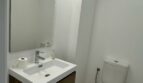 Modernes Badezimmer im Penthouse mit schwebendem Holzunterschrank, weißem Waschbecken und WC in Palma de Mallorca.