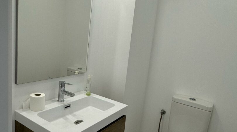 Modernes Badezimmer im Penthouse mit schwebendem Holzunterschrank, weißem Waschbecken und WC in Palma de Mallorca.