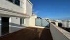 Sonnige Dachterrasse mit Holzdeck und Glasgeländer, Blick über die Dächer von Palma de Mallorca