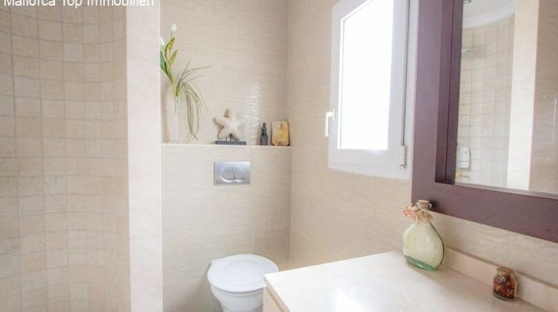 Bright bathroom with beige tiles, shower, toilet and window in the chalet with sea view in Puerto Adriano