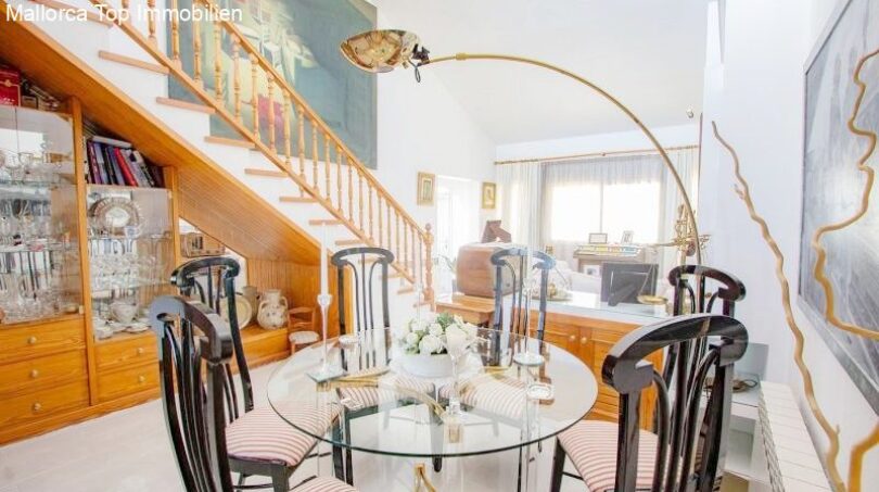 Elegant dining room with glass table, black designer chairs and open living area in the chalet in Puerto Adriano.