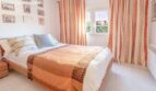 Bright bedroom of the chalet in Puerto Adriano with double bed, striped curtains and wall decoration.
