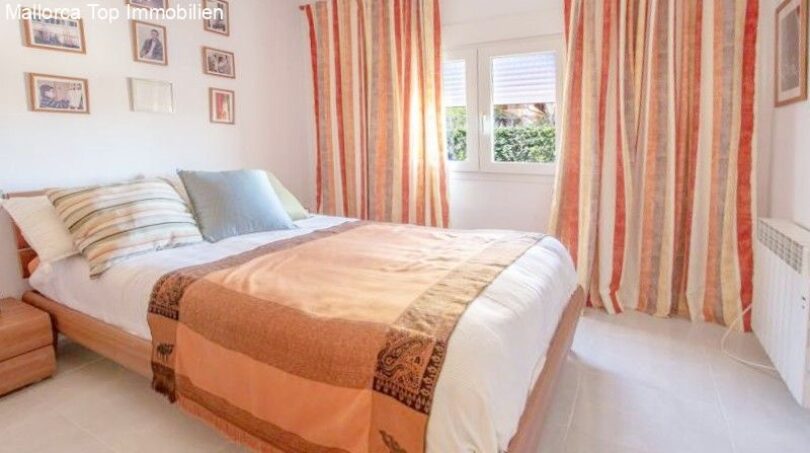 Bright bedroom of the chalet in Puerto Adriano with double bed, striped curtains and wall decoration.