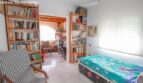 Bright bedroom in the Port Adriano chalet with single bed, bookshelves and striped armchair
