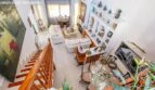 Bright living room with white sofas, wooden staircase, display wall and dining table in the Port Adriano chalet, Calvià