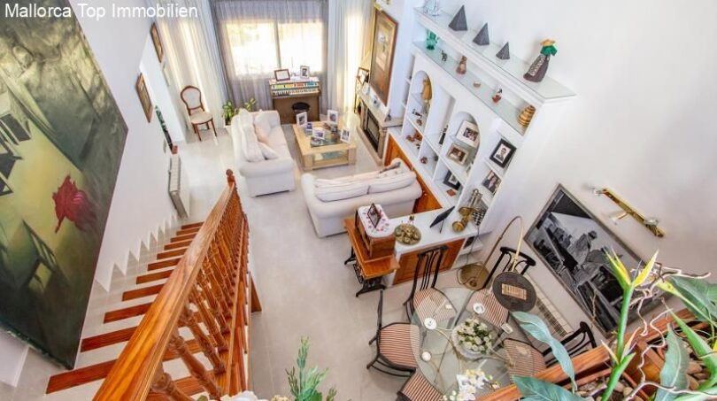 Bright living room with white sofas, wooden staircase, display wall and dining table in the Port Adriano chalet, Calvià