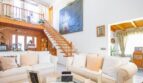 Bright living room with white sofas, wooden staircase, gallery and large artwork in Puerto Adriano chalet