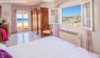 Bright bedroom with sea view, wooden wardrobe, radiator and purple accents in chalet, Puerto Adriano.