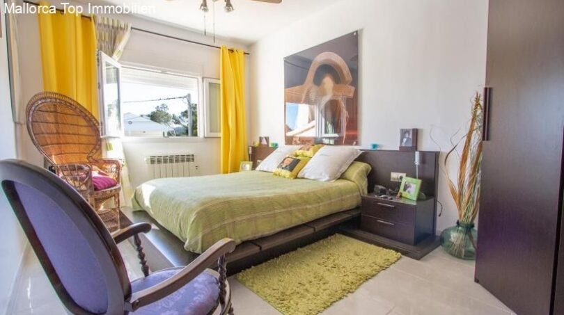Bright bedroom in Port Adriano chalet with double bed, yellow curtains and modern ambiance.