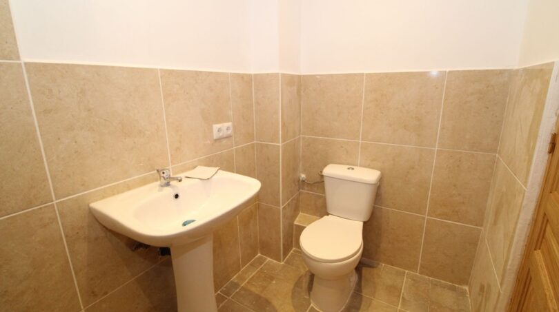 Helles Gäste-WC der Finca mit Waschbecken und WC, beige Marmoroptik-Fliesen, gepflegt und funktional.