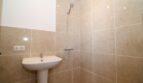 Helles Badezimmer der Finca mit beiger Fliesendusche, Handbrause und Waschbecken auf Säule.