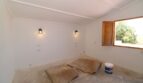 Renovierungsbedürftiges Zimmer der Finca in Son Ferriol mit Wandleuchten und Holzfenster zum Garten