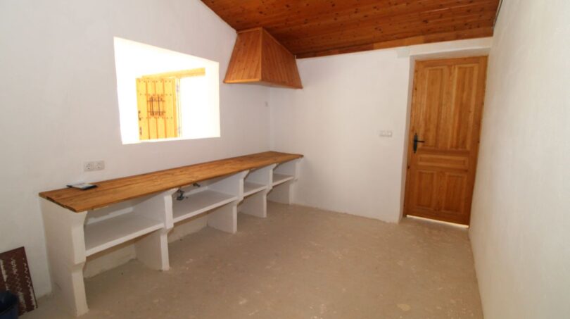 Rustikaler Nebenraum der Finca mit Holzdecke, eingebautem Regal und Dunstabzug in Son Ferriol