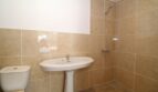 Gefliestes Badezimmer der Finca mit Waschbecken, WC und bodenebener Dusche in hellen Beige-Tönen.