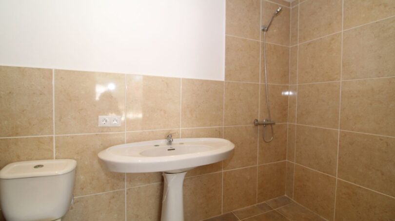 Gefliestes Badezimmer der Finca mit Waschbecken, WC und bodenebener Dusche in hellen Beige-Tönen.