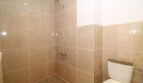 Gefliestes Duschbad der Finca in Son Ferriol mit bodenebener Dusche und WC, beige Marmoroptik-Fliesen.