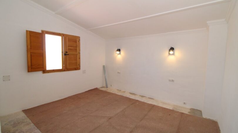 Leeres Schlafzimmer der Finca in Son Ferriol mit Holzfensterladen und zwei Wandleuchten