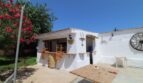 Rustikale Außenterrasse der Finca Son Ferriol mit weißer Fassade, Holztisch, Weinfass und dekorativem Wagenrad.